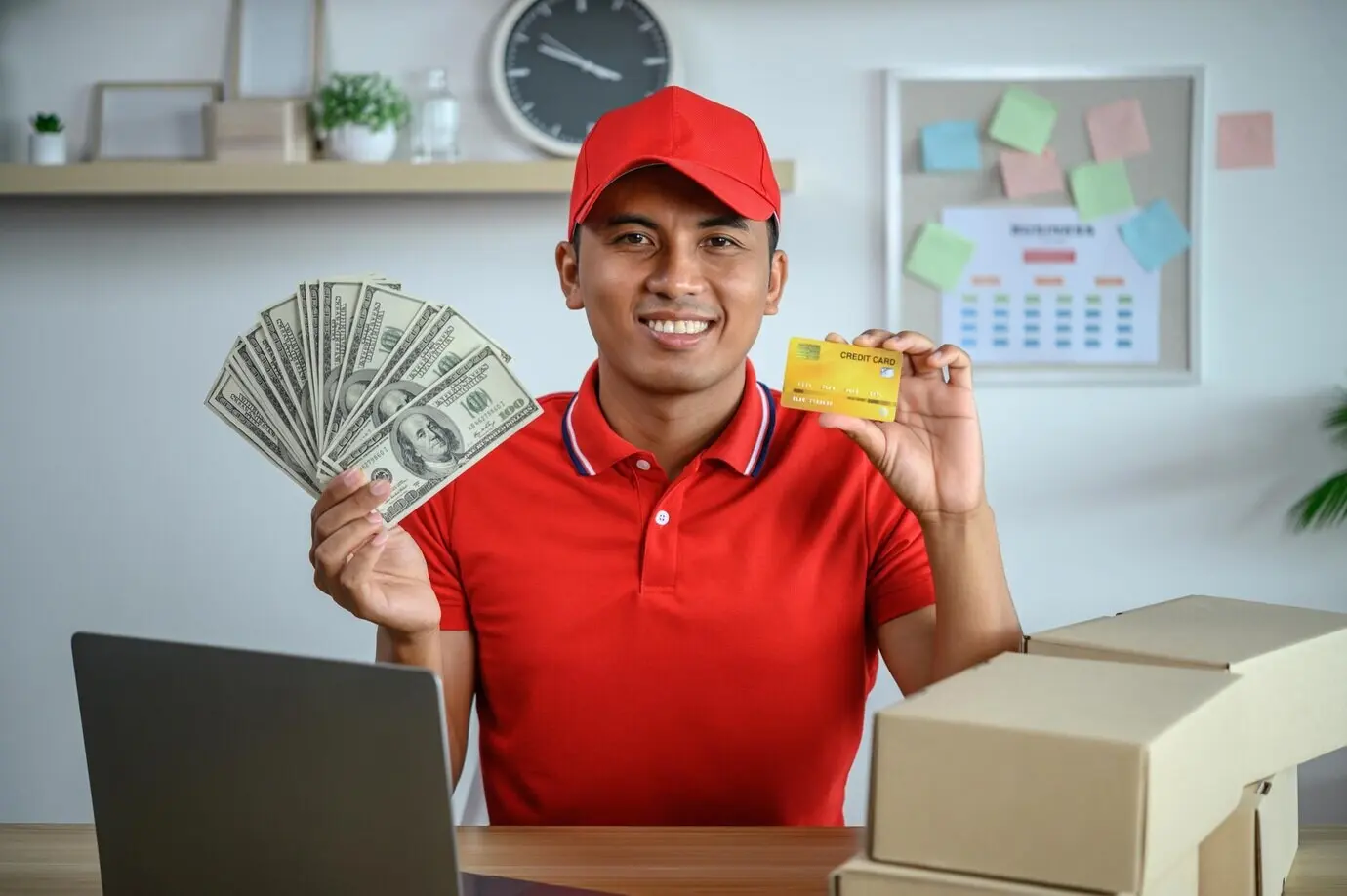 Ein männlicher Mitarbeiter bezahlt Waren über den Computer mit einer Kreditkarte.